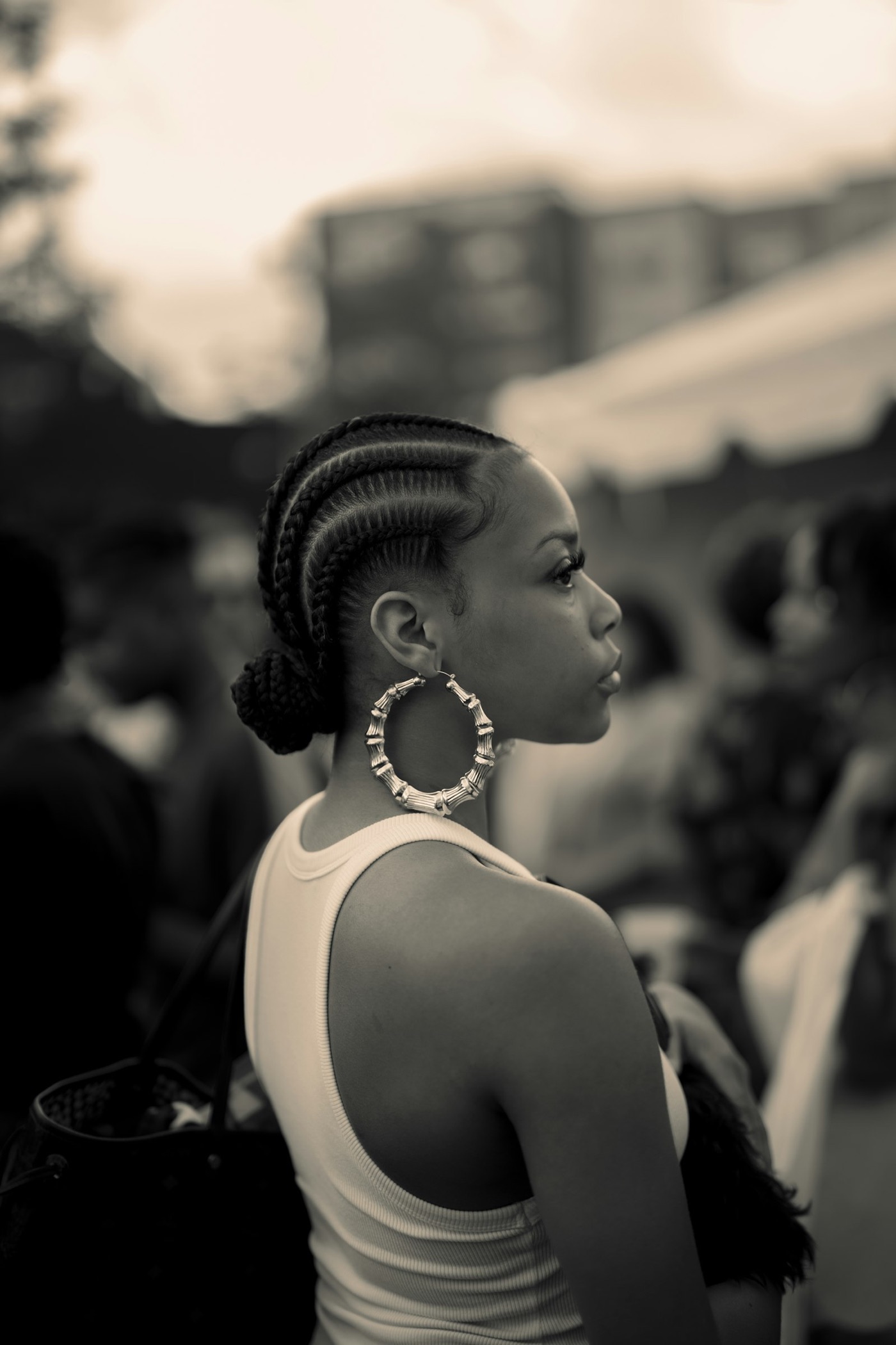 Editorial profile with long braids and bamboo hoop earrings in warm sepia light