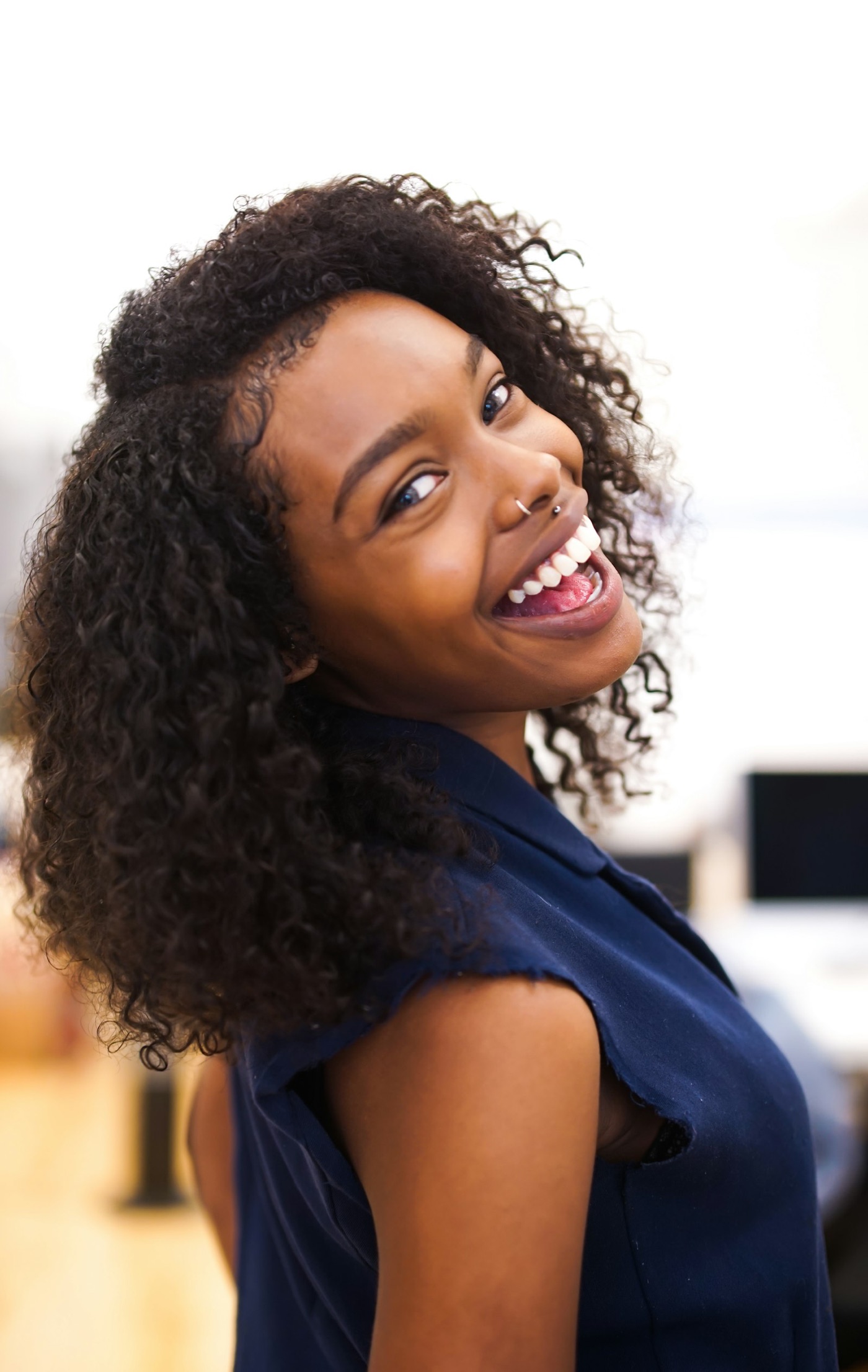 Woman glancing back and smiling, her defined dark curls catching the light