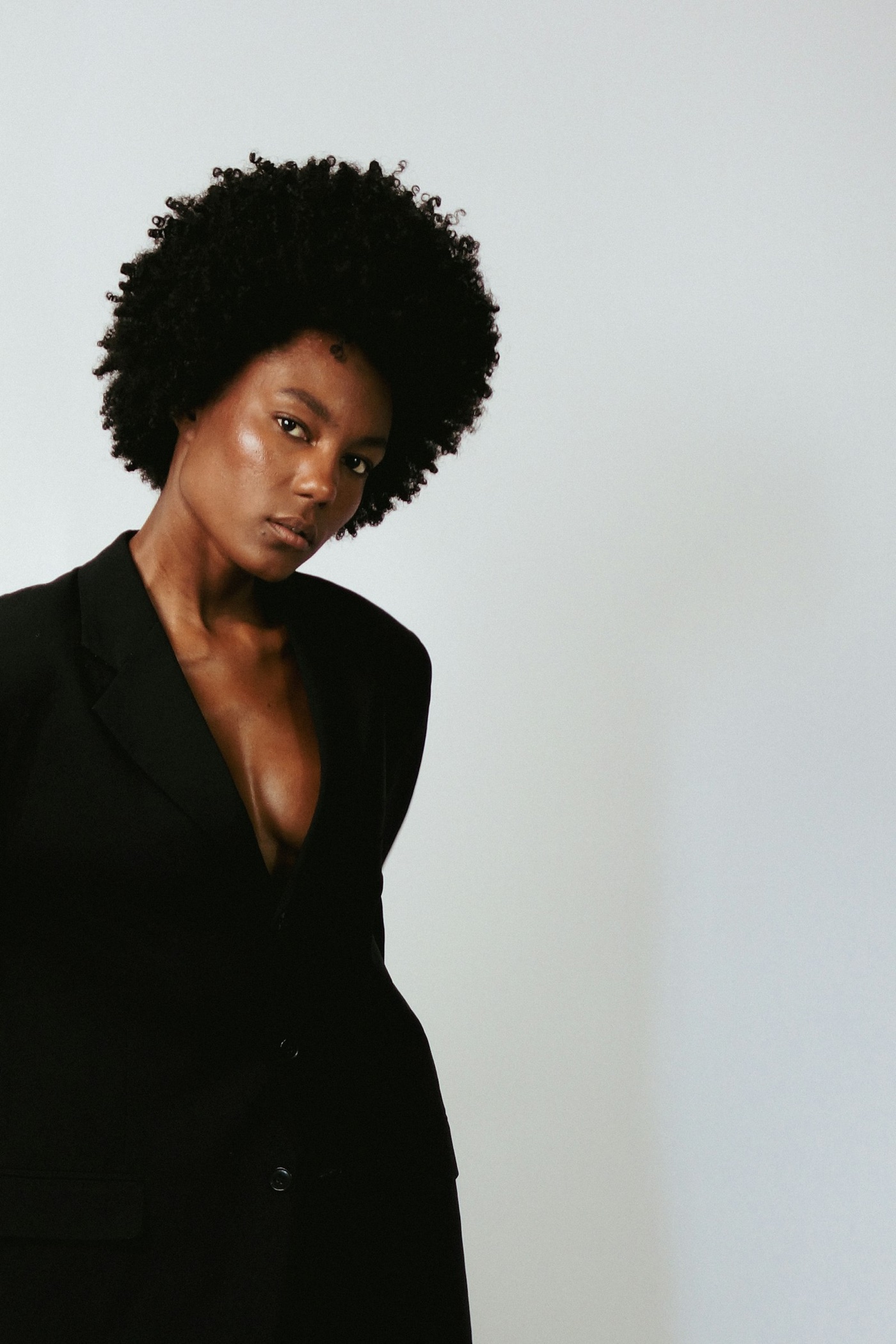 Mandy in a black blazer, natural curls framing a direct, confident gaze